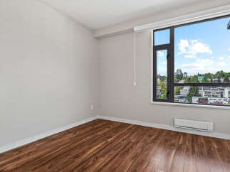 Experience modern living in this spacious room featuring elegant hardwood floors and a large window with stunning city views.