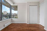 Experience modern living in this spacious room featuring a large window with city views and rich hardwood flooring.
