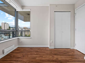 Experience modern living in this spacious room featuring a large window with city views and rich hardwood flooring.