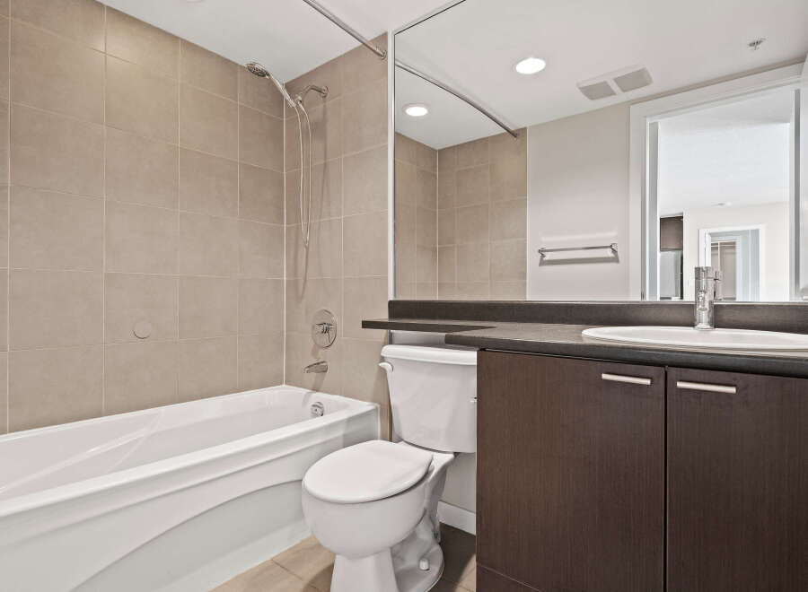 This modern bathroom features a deep soaking tub and a sleek vanity with ample storage.