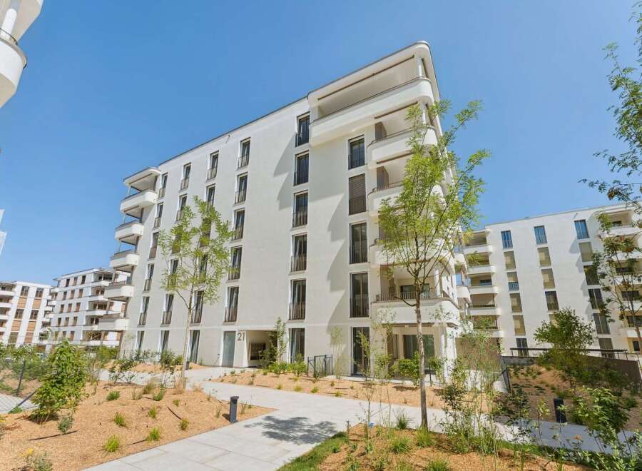 Discover modern living in this stunning white apartment building, featuring a contemporary design with clean lines and ample balconies.