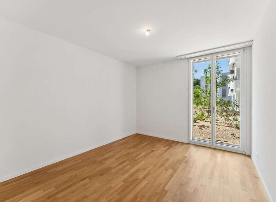 Experience modern living in this unfurnished room featuring a beautiful hardwood floor and a large window that floods the space with natural light.