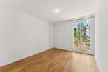 Experience modern living in this unfurnished room featuring a beautiful hardwood floor and a large window that floods the space with natural light.