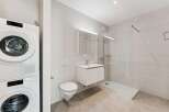 This modern bathroom features a stacked washer and dryer for ultimate convenience.