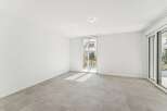 Experience modern living in this bright and airy empty room, featuring sleek tiled flooring and expansive glass doors that open to a serene outdoor space.