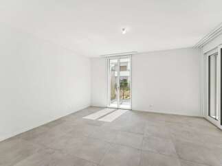 Experience modern living in this bright and airy empty room, featuring sleek tiled flooring and expansive glass doors that open to a serene outdoor space.
