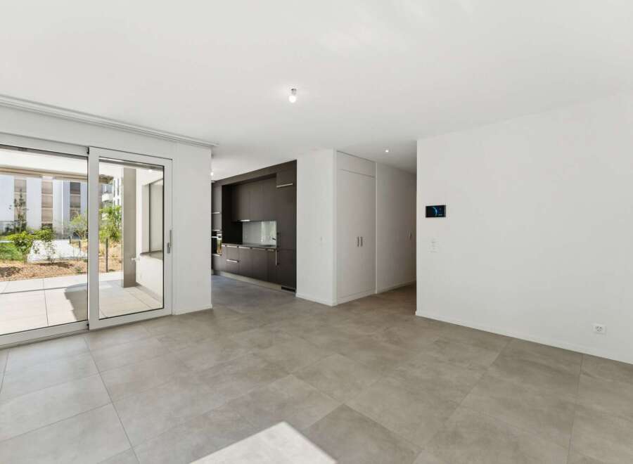 Step into this modern open-plan living space featuring a sleek, dark-wood kitchen with integrated appliances.