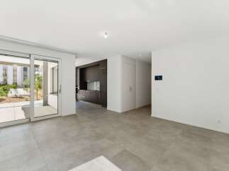 Step into this modern open-plan living space featuring a sleek, dark-wood kitchen with integrated appliances.