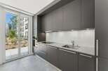 Experience modern living in this sleek, contemporary kitchen featuring dark gray cabinetry and a pristine white backsplash.