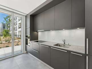Experience modern living in this sleek, contemporary kitchen featuring dark gray cabinetry and a pristine white backsplash.