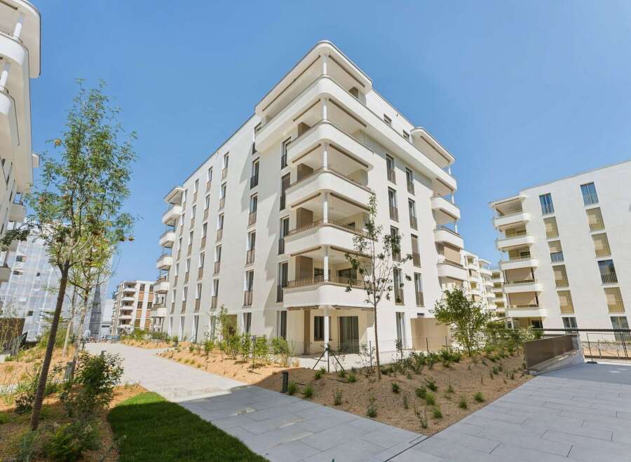 Discover modern living in this stunning apartment complex featuring sleek white facades and expansive balconies perfect for enjoying the outdoors.