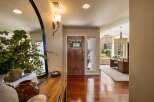 Step into this inviting entryway featuring a warm wooden front door with glass panes, complemented by a large arched mirror and a sleek console table.