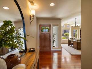 Step into this inviting entryway featuring a warm wooden front door with glass panes, complemented by a large arched mirror and a sleek console table.
