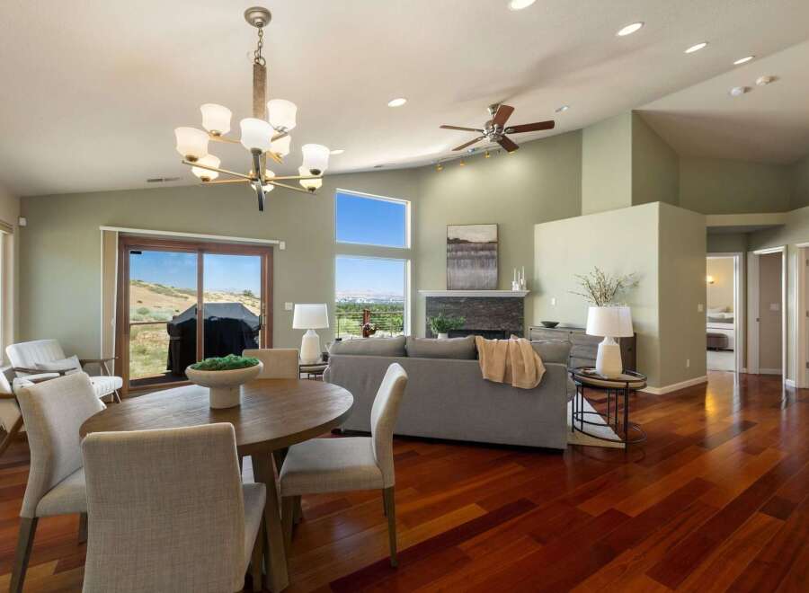 Experience breathtaking views from this stunning living and dining area, featuring a vaulted ceiling with a modern chandelier and a cozy fireplace.