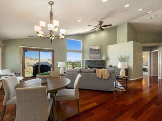 Experience breathtaking views from this stunning living and dining area, featuring a vaulted ceiling with a modern chandelier and a cozy fireplace.