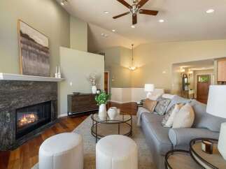 Experience elegant living in this spacious great room, featuring a stunning stone fireplace and vaulted ceilings with a ceiling fan.