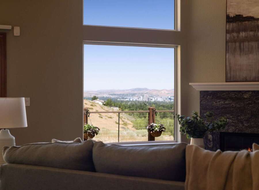 Experience breathtaking panoramic views from this stunning home, featuring expansive windows that showcase a vibrant cityscape and rolling hills.