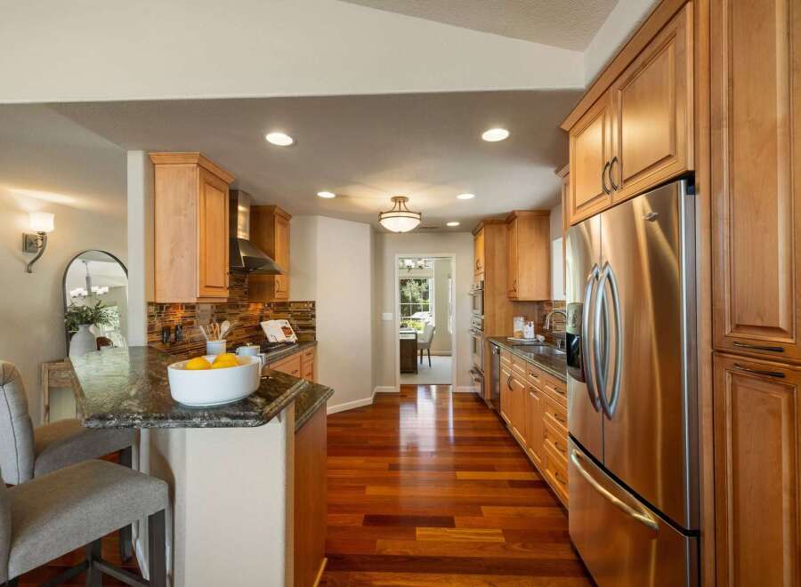 This beautifully remodeled kitchen features warm, natural wood cabinetry and gleaming stainless steel appliances, including a large side-by-side refrigerator.