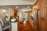 This beautifully remodeled kitchen features warm, natural wood cabinetry and gleaming stainless steel appliances, including a large side-by-side refrigerator.