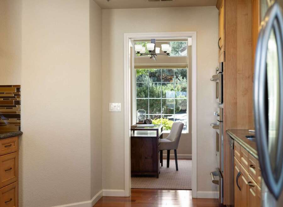 Step into a charming home office space, bathed in natural light from a large window overlooking lush greenery.
