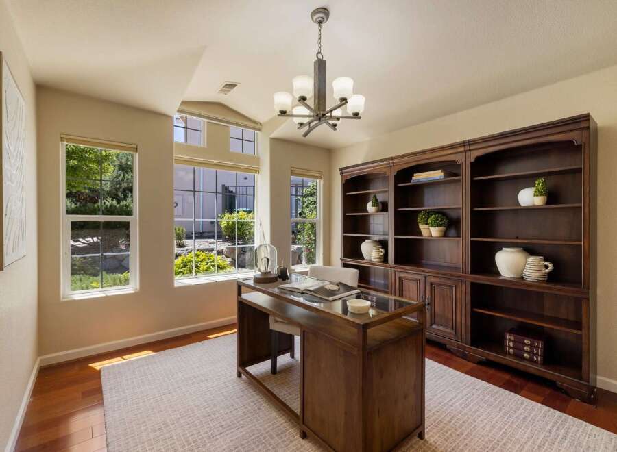 This elegant home office features a spacious wooden desk with a glass top, perfect for productivity.