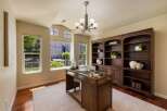 This elegant home office features a spacious wooden desk with a glass top, perfect for productivity.