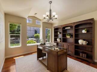This elegant home office features a spacious wooden desk with a glass top, perfect for productivity.