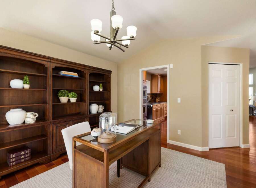 Discover this elegant home office featuring a rich mahogany built-in bookshelf and a stylish wooden desk with a glass top.