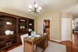 Discover this elegant home office featuring a rich mahogany built-in bookshelf and a stylish wooden desk with a glass top.