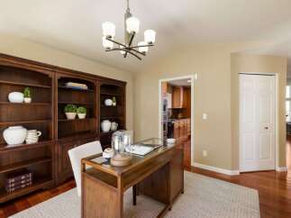 Discover this elegant home office featuring a rich mahogany built-in bookshelf and a stylish wooden desk with a glass top.
