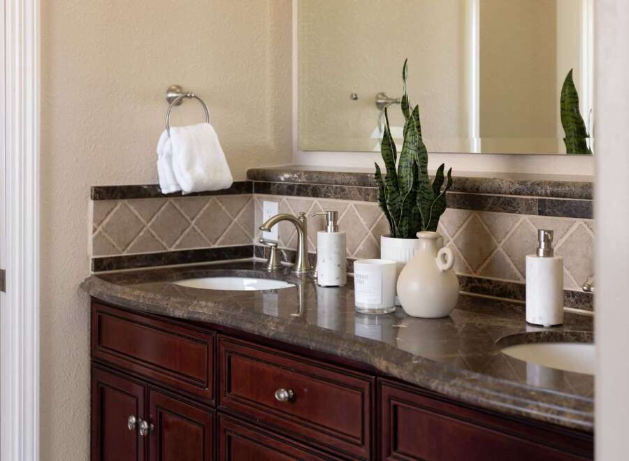 This elegant bathroom vanity features a rich, dark wood cabinet base topped with a polished granite countertop.