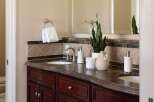 This elegant bathroom vanity features a rich, dark wood cabinet base topped with a polished granite countertop.