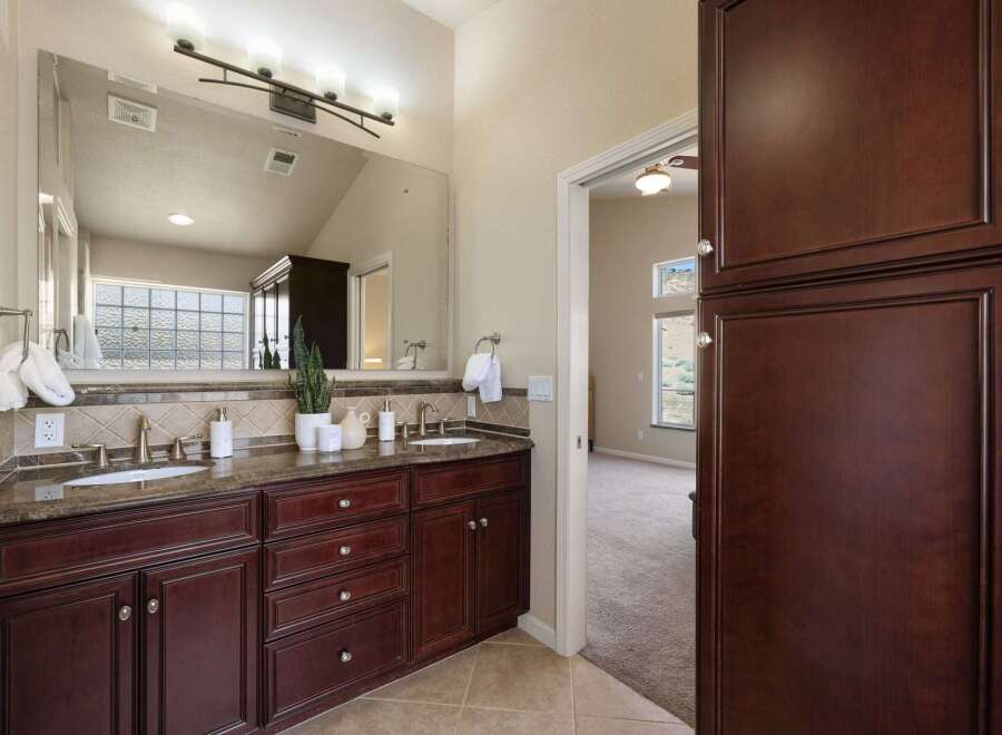 This spacious bathroom features a double vanity with granite countertops and dark wood cabinetry, offering ample storage.