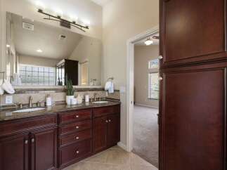 This spacious bathroom features a double vanity with granite countertops and dark wood cabinetry, offering ample storage.