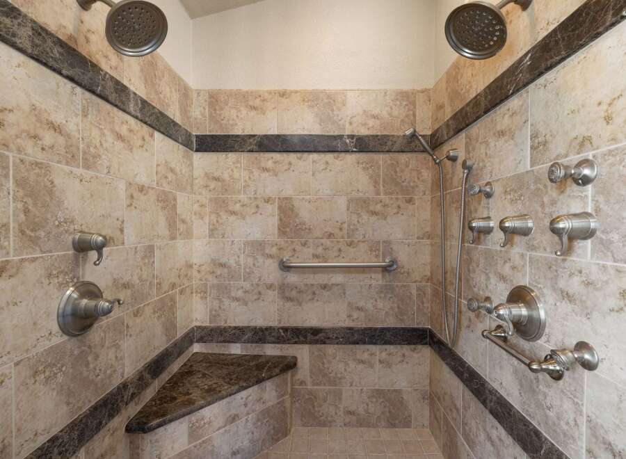 Experience ultimate relaxation in this luxurious custom shower, featuring dual shower heads, multiple body jets, and a convenient built-in bench.