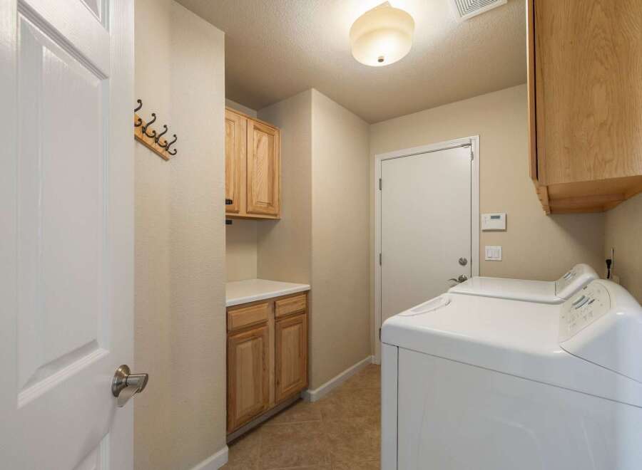 This laundry room offers ample storage with both upper and lower cabinets, perfect for organizing supplies.