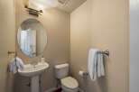 This powder room features a pedestal sink with a chrome faucet and a round mirror above.