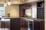 This elegant home bar features rich, dark wood cabinetry with glass-fronted upper cabinets and a built-in wine rack.