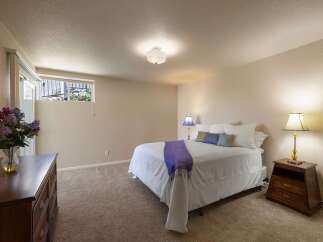 Discover comfort and style in this inviting bedroom, featuring a plush queen-size bed adorned with crisp white linens and decorative pillows.