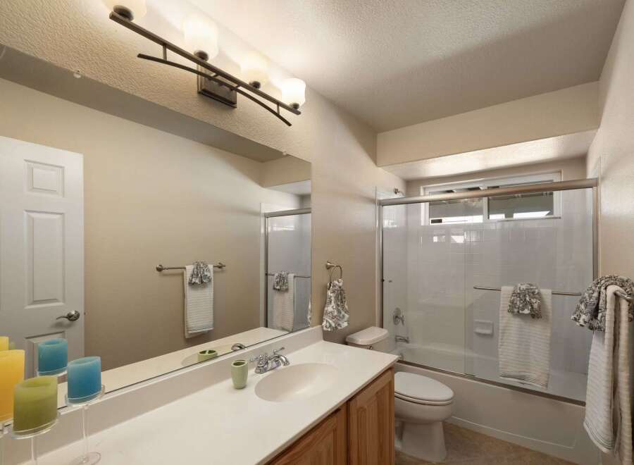 This bright and airy bathroom features a spacious vanity with ample counter space and a large mirror, perfect for your morning routine.