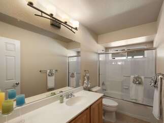 This bright and airy bathroom features a spacious vanity with ample counter space and a large mirror, perfect for your morning routine.