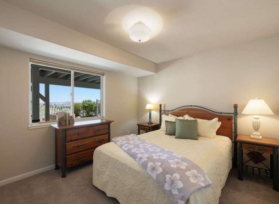 This charming bedroom offers a comfortable retreat with a queen-sized bed featuring a wooden headboard and plush bedding.