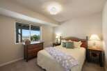 This charming bedroom offers a comfortable retreat with a queen-sized bed featuring a wooden headboard and plush bedding.