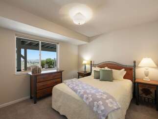 This charming bedroom offers a comfortable retreat with a queen-sized bed featuring a wooden headboard and plush bedding.