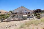 Enjoy outdoor living with a spacious deck overlooking a fenced backyard featuring raised garden beds and a greenhouse.