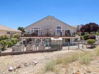 Enjoy outdoor living with a spacious deck overlooking a fenced backyard featuring raised garden beds and a greenhouse.