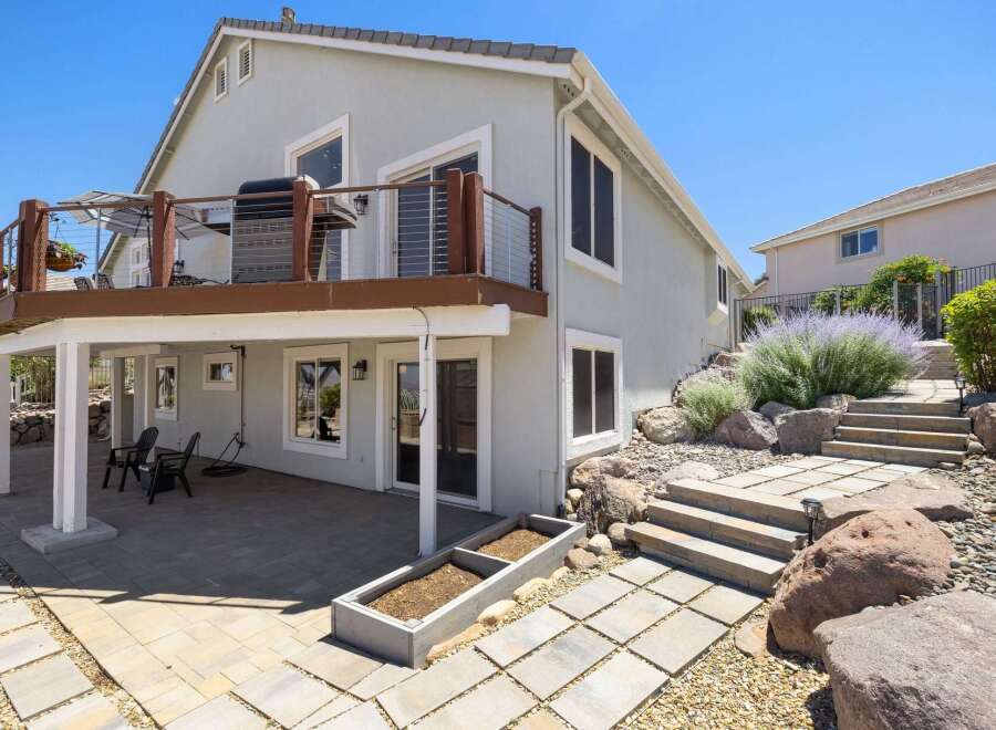 Enjoy outdoor living with this multi-level backyard featuring a spacious deck with a grill and seating area, perfect for entertaining.