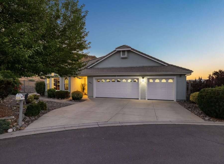 This charming single-story home features a welcoming facade with a well-maintained lawn and a spacious driveway leading to a two-car garage.