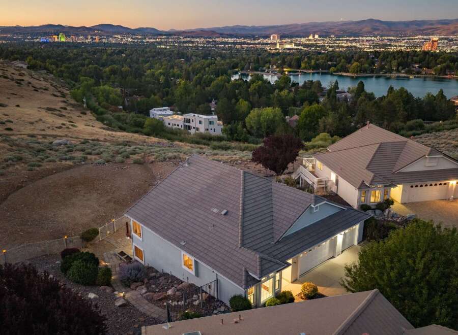 Experience breathtaking panoramic views from this stunning hillside estate, perfectly situated to capture the vibrant city lights and serene lake at dusk.