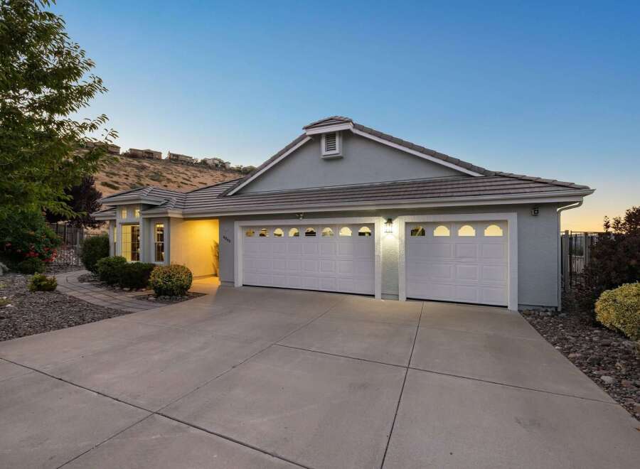 This stunning single-story home features a welcoming facade with a spacious driveway leading to a large, attached three-car garage.